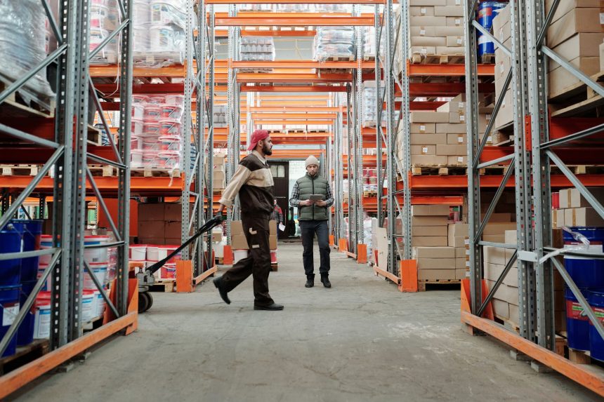 Dois trabalhadores organizam mercadorias em um corredor de armazém.