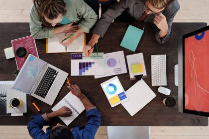 Equipe diversa reunida em torno de uma mesa, colaborando em um projeto em um escritório moderno.