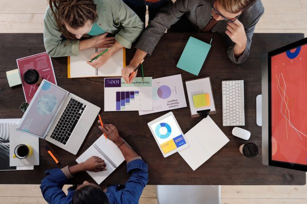 Equipe diversa reunida em torno de uma mesa, colaborando em um projeto em um escritório moderno.