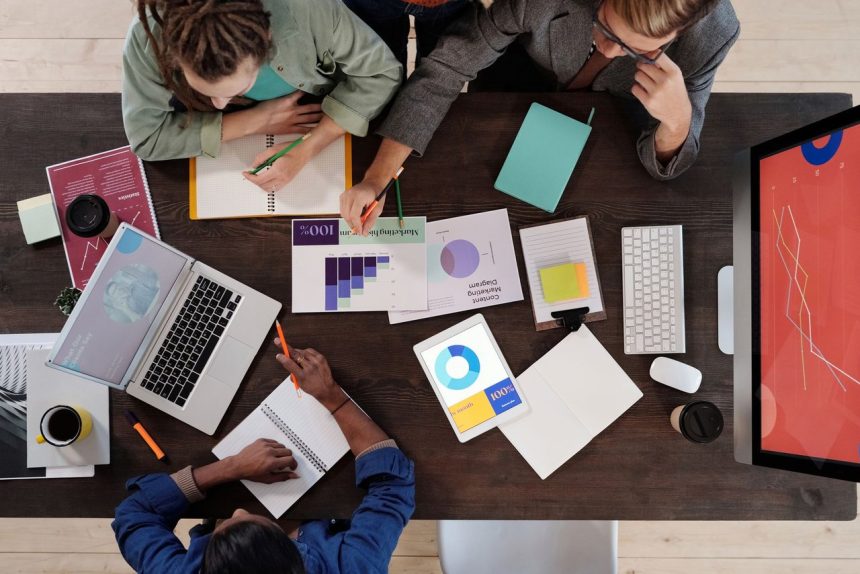 Equipe diversa reunida em torno de uma mesa, colaborando em um projeto em um escritório moderno.