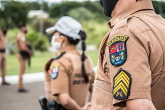 Policiais uniformizados permanecem em formação em uma área externa durante uma ação de segurança.
