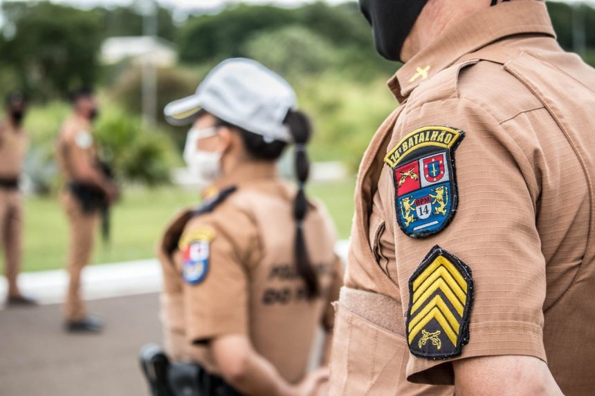 Policiais uniformizados permanecem em formação em uma área externa durante uma ação de segurança.