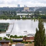 Vista aérea de uma cidade com ruas e construções parcialmente submersas por águas de enchente.